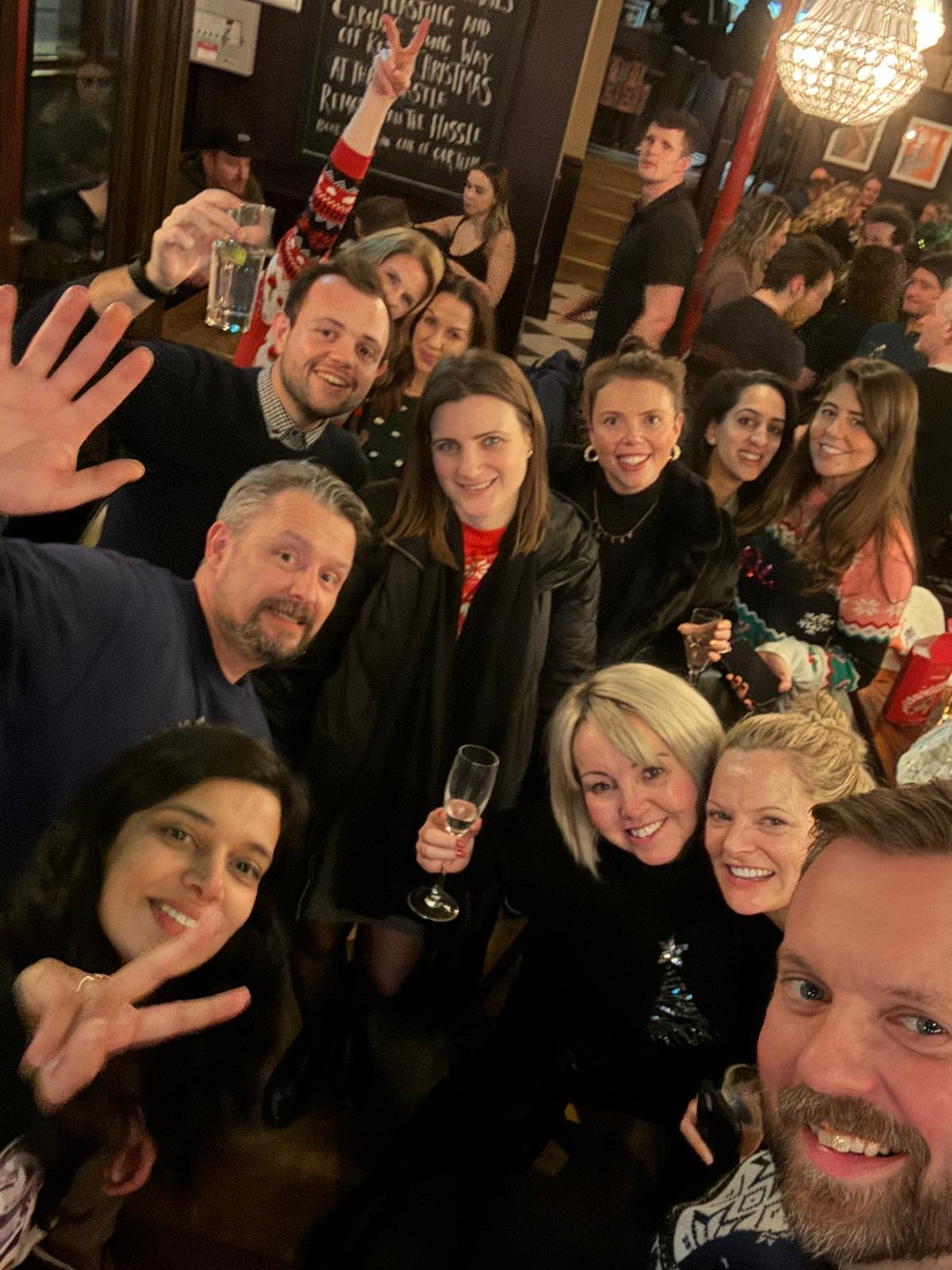 A group of friends raising glasses in a busy London pub